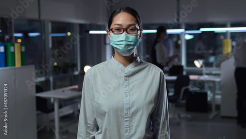 Asian woman in safety mask in office posing at camera