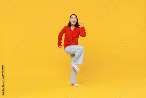 Full size body length vivid young woman of Asian ethnicity 20s years old in casual clothes doing winner gesture celebrate clenching fists say yes isolated on plain yellow background studio portrait.
