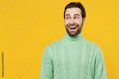 Young surprised amazed fun cool happy man 20s wearing mint knitted sweater look aside on workspace area mock up isolated on plain yellow background studio portrait. People lifestyle fashion concept. © ViDi Studio