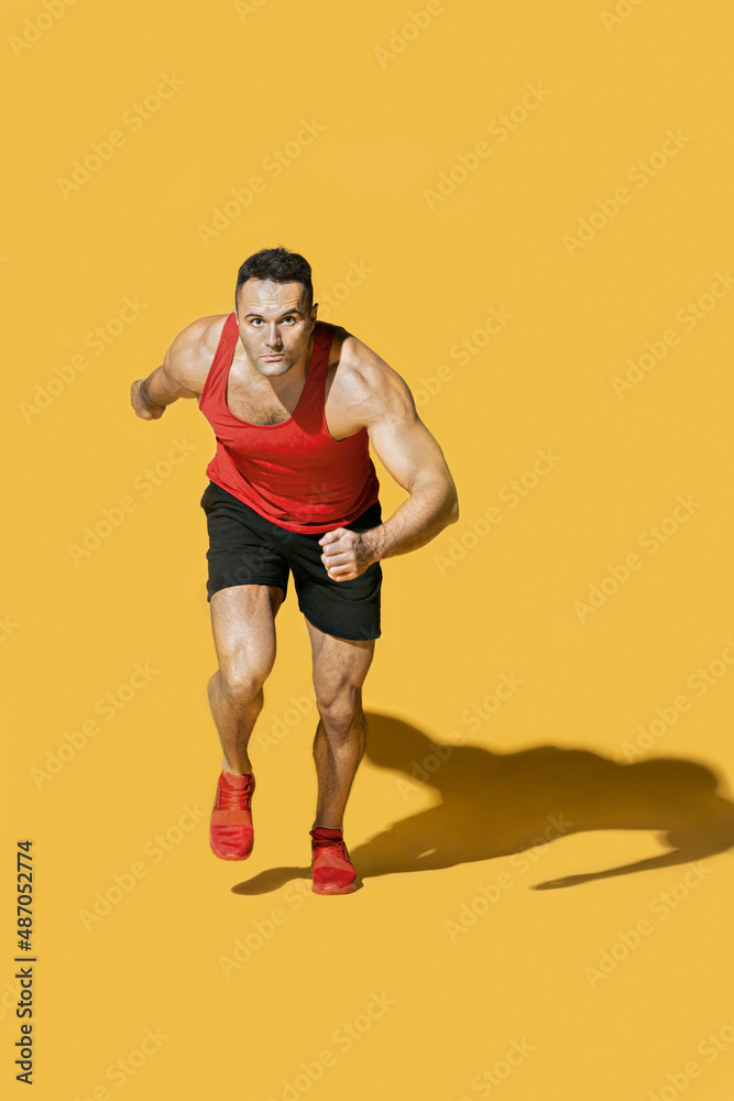 Studio portrait determined, athletic man running on yellow background
Studio portrait determined, athletic man running on yellow background