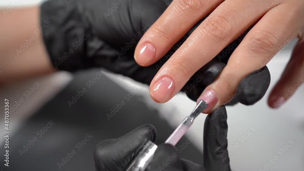 Hardware manicure in a beauty salon, female hands applying gel polish, covering the nail plate, woman's nails for beauty Hardware manicure in a beauty salon, female hands applying gel polish, covering the nail plate, woman's nails for beauty