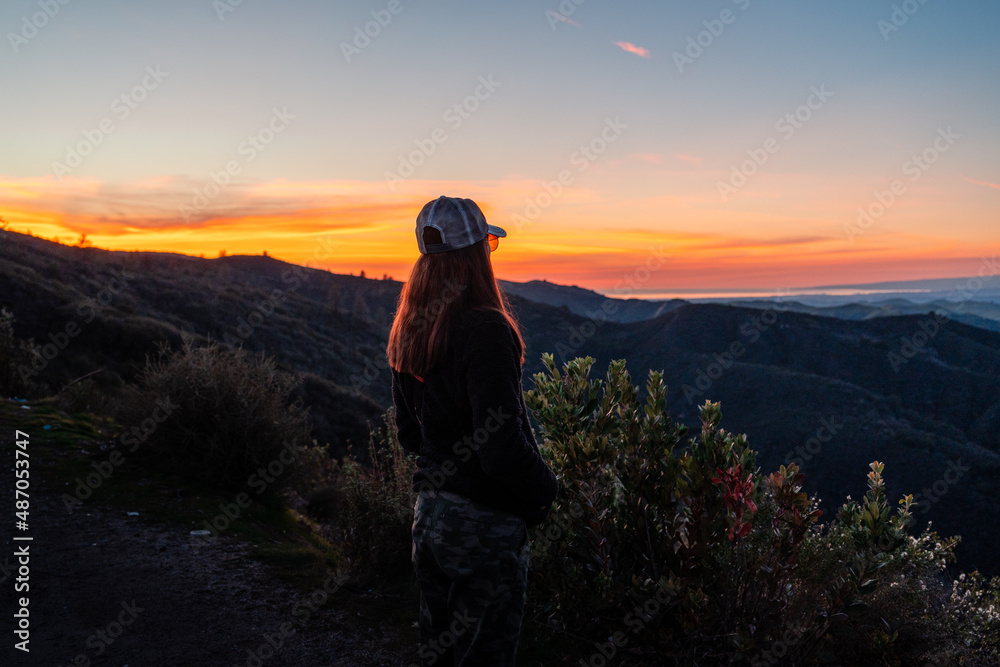 Fototapeta premium Sunset Over Mountains with Woman Looking Away