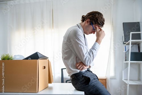 Business man stressed and tired from work. Businessman with boxes for personal items on desk. resignation and vacancies and job changes. photo