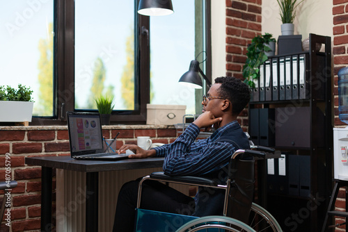 Foto African american with chronic health condition using laptop to analyze marketing statistics at desk