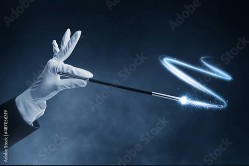 Magician hand holding magic wand on dark background