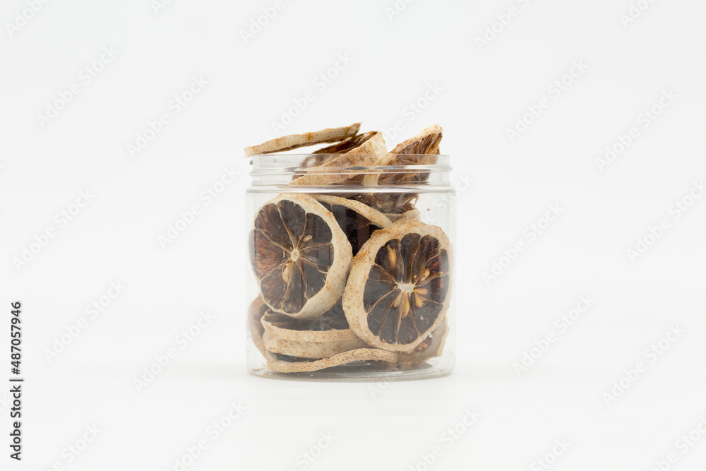 dried lemon slices in a transparent jar on a white background dried lemon slices in a transparent jar on a white background