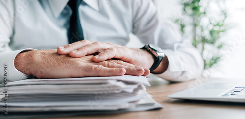 Insurance agent with stack of policy contracts on office desk photo