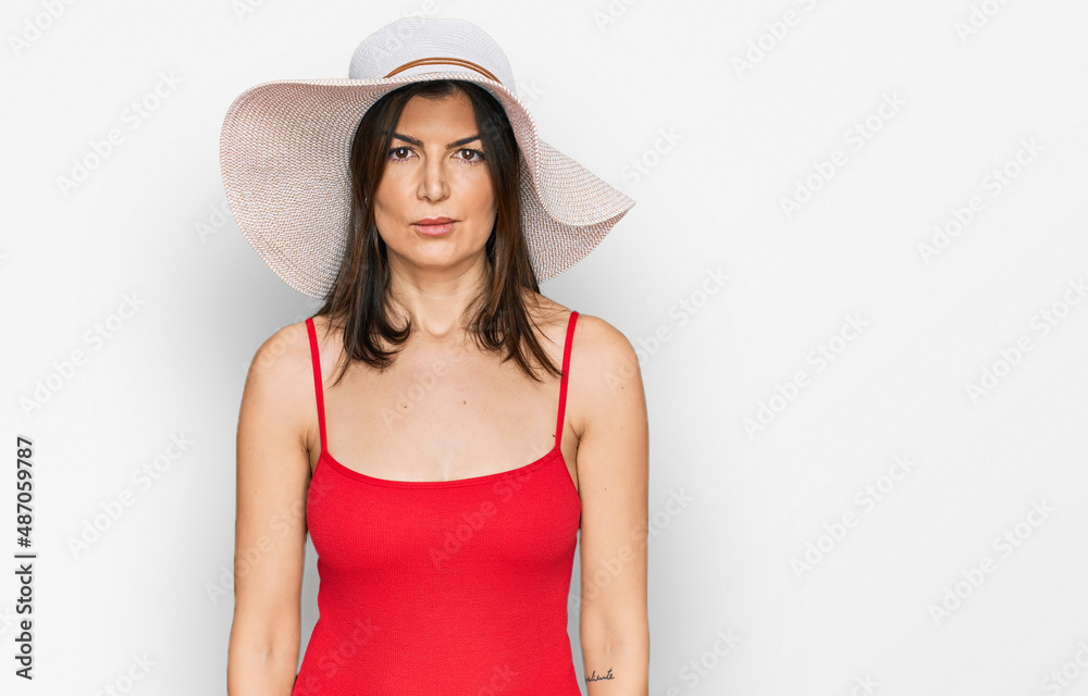 Beautiful brunette woman wearing swimsuit and summer hat depressed and worry for distress, crying angry and afraid. sad expression. Beautiful brunette woman wearing swimsuit and summer hat depressed and worry for distress, crying angry and afraid. sad expression.