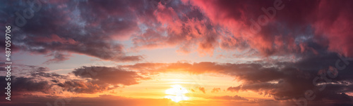 Yellow and warm sunset from gray clouds. Panorama of the dramatic evening sky above the horizon.