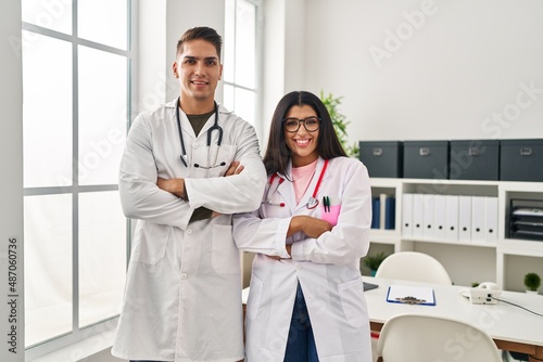 Young doctors wearing uniform and stethoscope at the clinic happy face smiling with crossed arms looking at the camera. positive person.