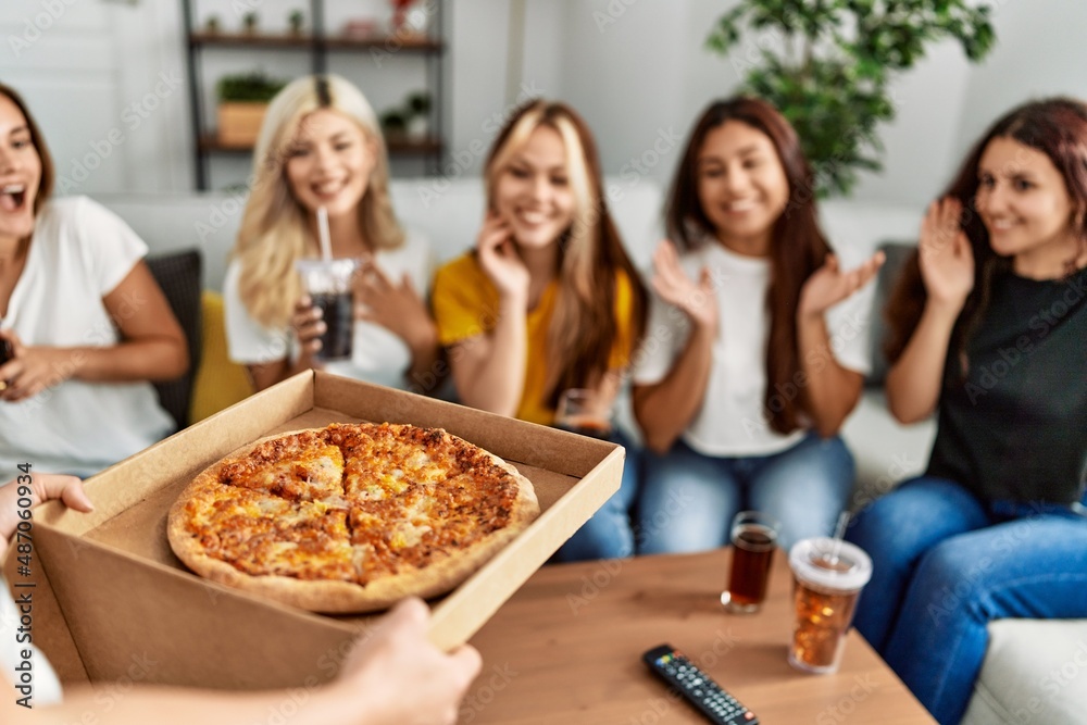 Group of young friends woman surprise for italian pizza sitting on the sofa at home. Group of young friends woman surprise for italian pizza sitting on the sofa at home.