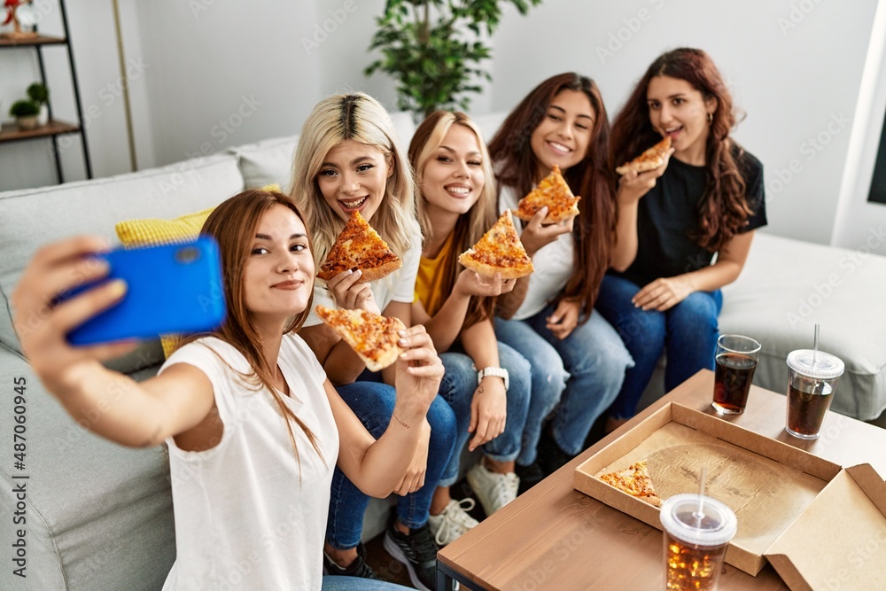 Group of young woman friends make selfie by the smartphone eating pizza at home.