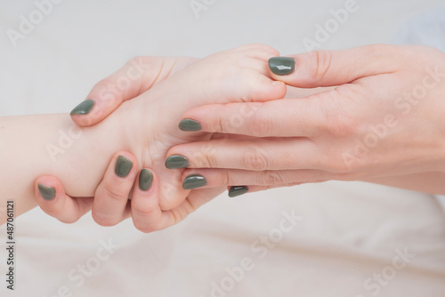 Baby's small legs in mom's hands, close-up. The concept of family happiness, loving parents. Baby care, massage. Background for Mother's day, baby's day. Touching mother and child