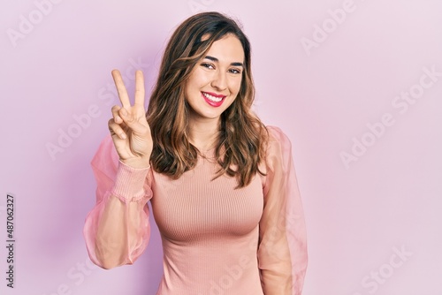 Young hispanic girl wearing casual clothes showing and pointing up with fingers number two while smiling confident and happy. © Krakenimages.com