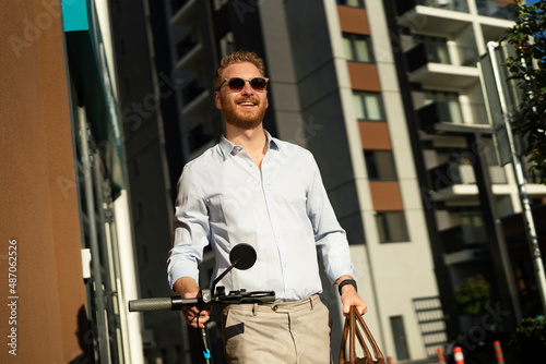 Young stylish businessman with e-scooter. Portrait of handsome man outdoors...