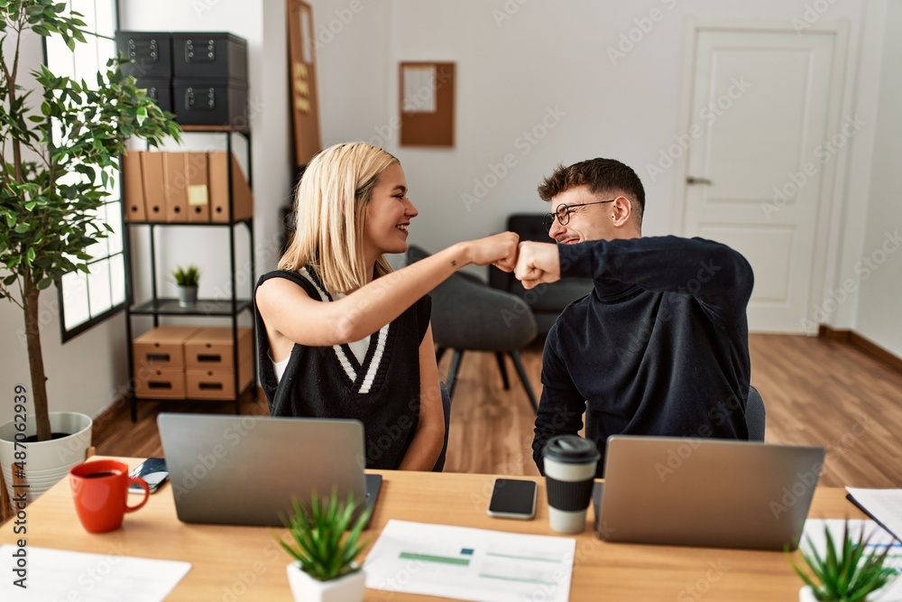 Two business workers smiling happy bump fists at the office. Two business workers smiling happy bump fists at the office.