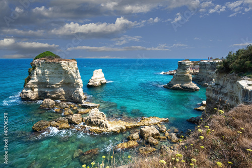 Melendugno,province of Lecce, Puglia, Italy. August 2021. The stacks of Sant'Andrea are a point of naturalistic attraction: the amazing landscape suggests a tropical destination. People taking a bath.