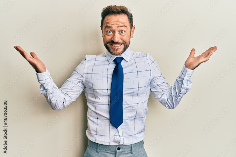Middle age businessman wearing business shirt and tie clueless and confused with open arms, no idea and doubtful face. Middle age businessman wearing business shirt and tie clueless and confused with open arms, no idea and doubtful face.