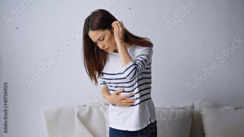 Fotografie brunette woman touching painful belly while suffering from abdominal hurt