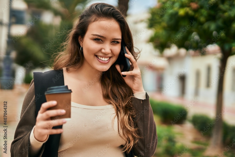 Young hispanic tourist woman talking on the smartphone and drinking coffee at the city. Young hispanic tourist woman talking on the smartphone and drinking coffee at the city.