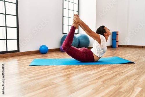Young hispanic woman stretching at sport center