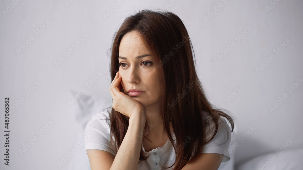 upset and thoughtful woman holding hand near face while sitting at home upset and thoughtful woman holding hand near face while sitting at home
