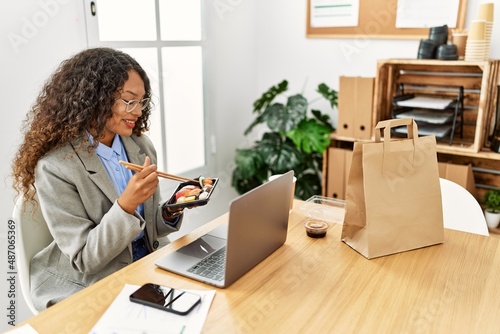 Young latin woman smiling confident eating sushi at office