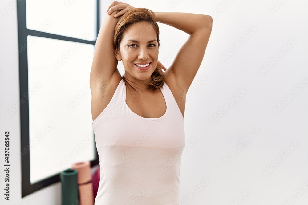 Young latin woman smiling confident stretching at sport center