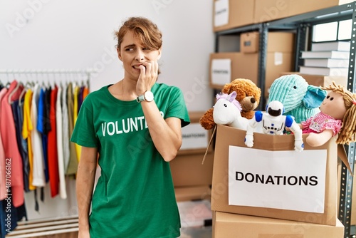 Beautiful caucasian woman wearing volunteer t shirt at donations stand looking stressed and nervous with hands on mouth biting nails. anxiety problem.