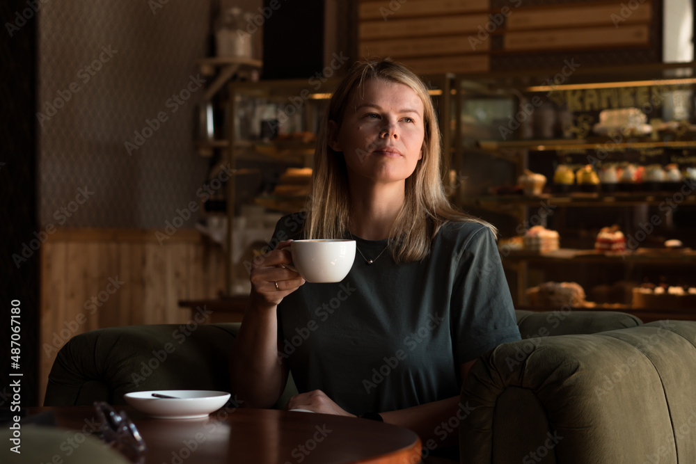 Beautiful blonde woman sits in coffeehouse and bakery and drinks cappuccino coffee Beautiful blonde woman sits in coffeehouse and bakery and drinks cappuccino coffee