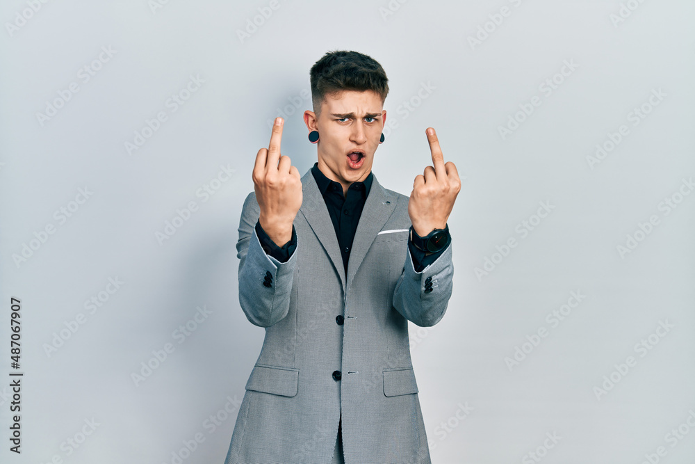 Young caucasian boy with ears dilation wearing business jacket showing middle finger doing fuck you bad expression, provocation and rude attitude. screaming excited Young caucasian boy with ears dilation wearing business jacket showing middle finger doing fuck you bad expression, provocation and rude attitude. screaming excited