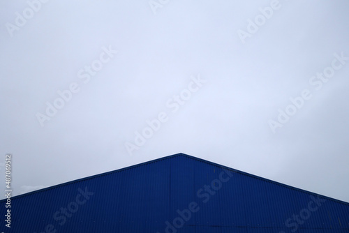 Roof of industrial warehouse against gray sky.