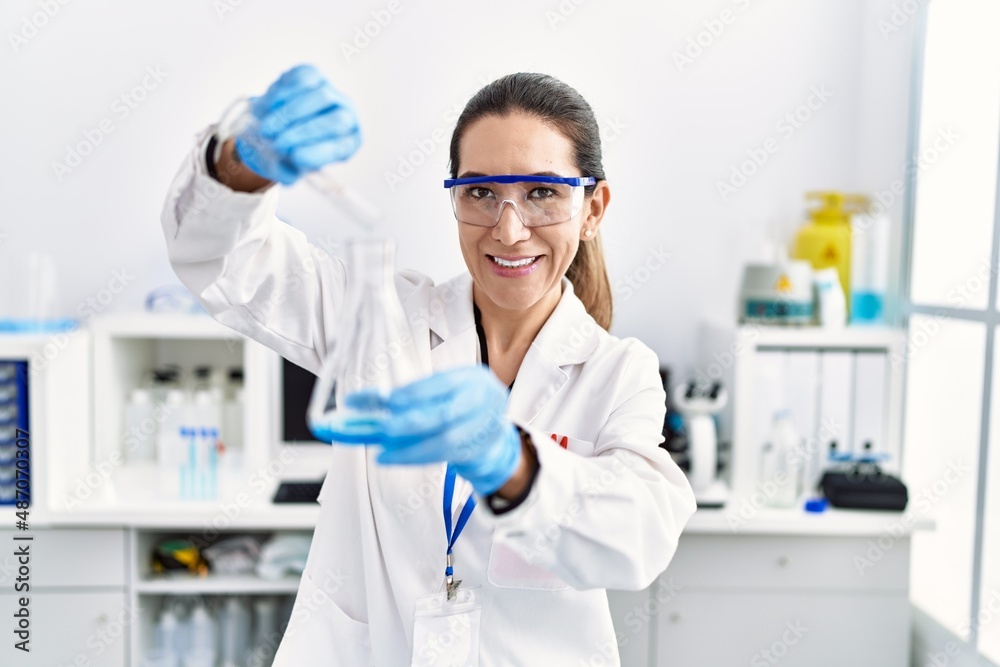 Young hispanic woman wearing scientist uniform holding test tube at laboratory Young hispanic woman wearing scientist uniform holding test tube at laboratory