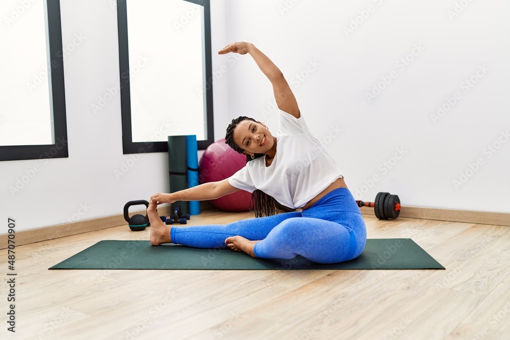 Fototapeta premium Young african american woman smiling confident stretching at sport center