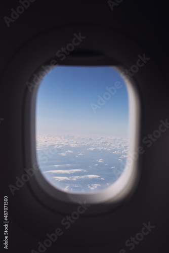 Window of airplane during flight above clouds on beautiful sunny day..