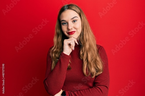 Young blonde woman wearing turtleneck sweater looking confident at the camera with smile with crossed arms and hand raised on chin. thinking positive. © Krakenimages.com