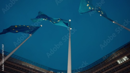 European Union flags in a row waving at night in the wind in front of European Commission, Berlaymont building in central Brussels city, Belgium. photo