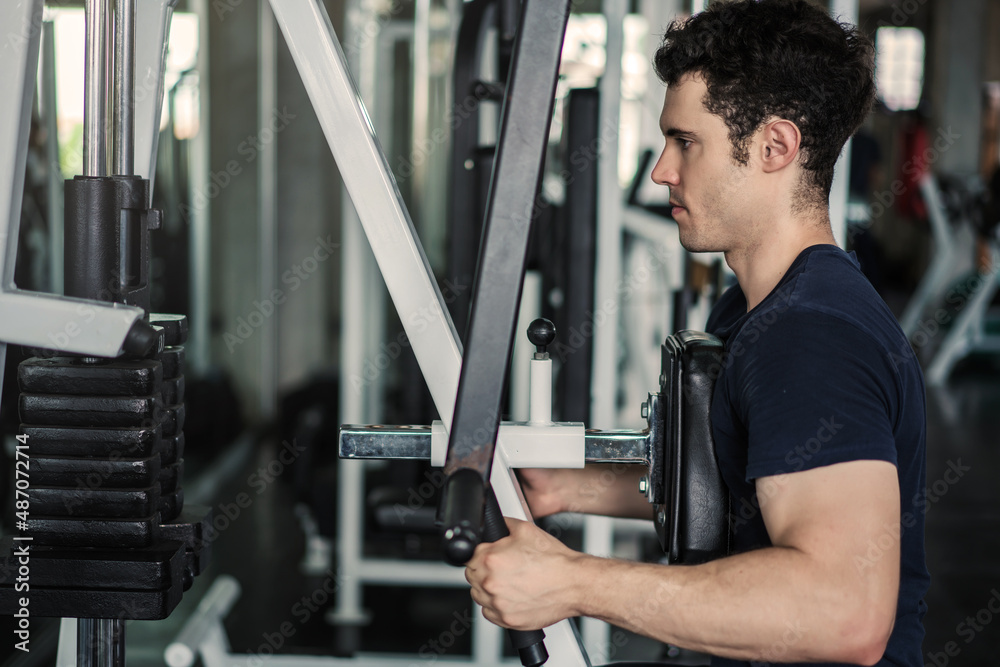 Sportsman or Handsome man lowering weight of fitness machine and working out in the fitness gym Sportsman or Handsome man lowering weight of fitness machine and working out in the fitness gym