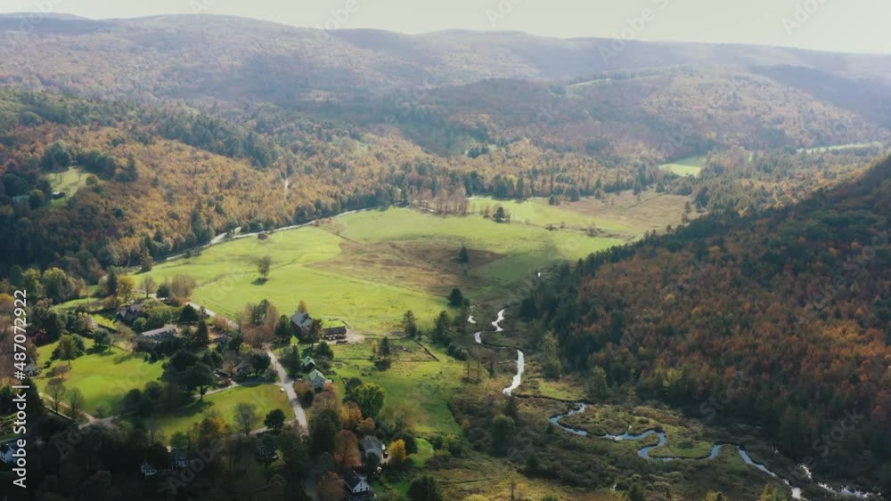 Aerial forwarding shot of rural landscape with the view of a village by the side of hills covered with forest on a cloudy day in Litchfield county, Connecticut,USA. Aerial forwarding shot of rural landscape with the view of a village by the side of hills covered with forest on a cloudy day in Litchfield county, Connecticut,USA.