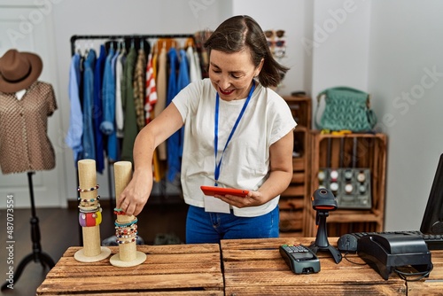 Middle age hispanic woman working using tablet device at retail shop