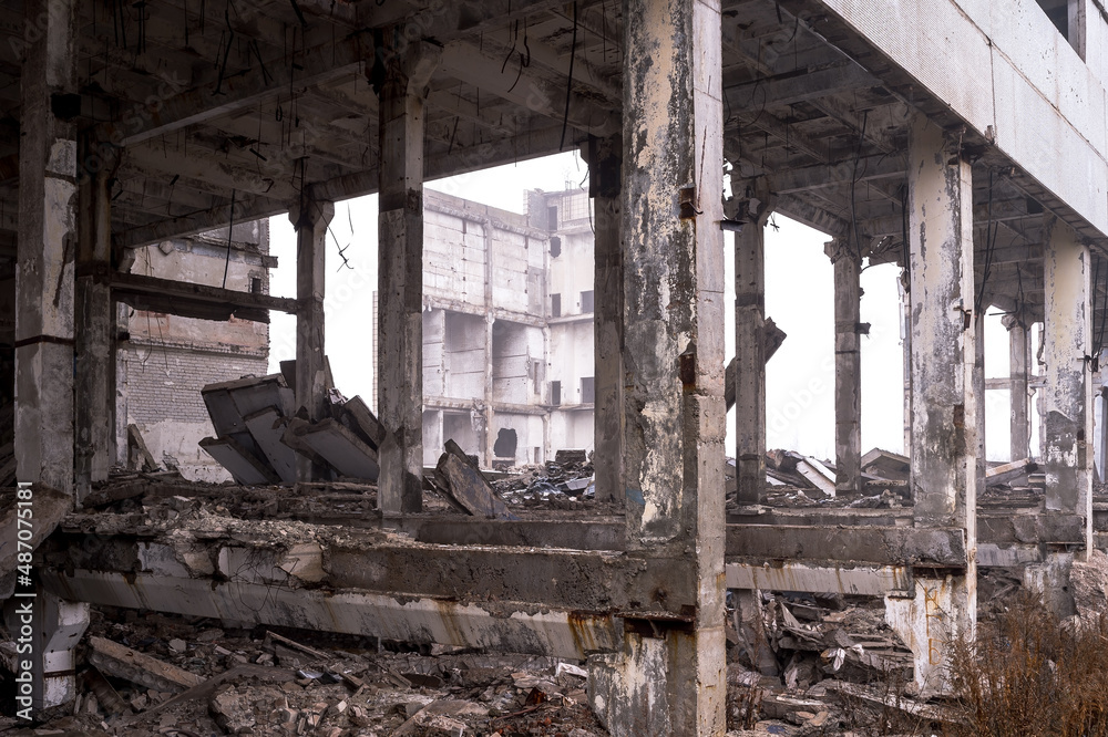 The frame of a large destroyed building with piles of gray concrete fragments of beams, bricks and construction debris. Background The frame of a large destroyed building with piles of gray concrete fragments of beams, bricks and construction debris. Background