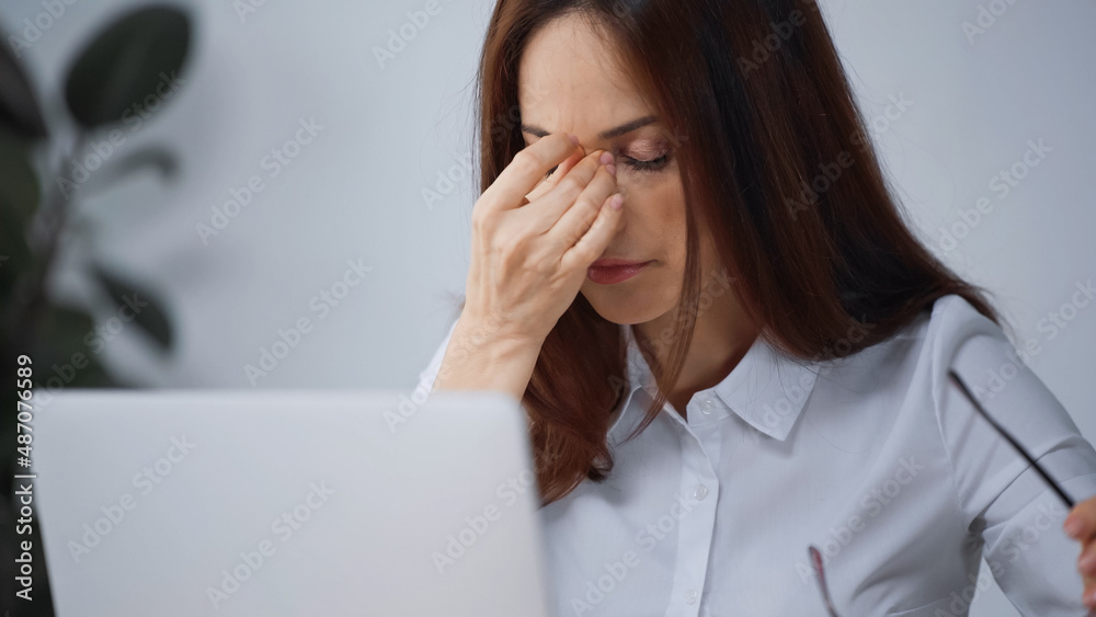 tired businesswoman with closed eyes suffering from headache in office tired businesswoman with closed eyes suffering from headache in office