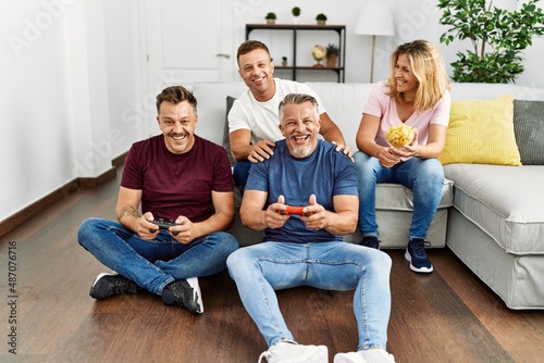 Group of middle age friends smiling happy playing video game at home.