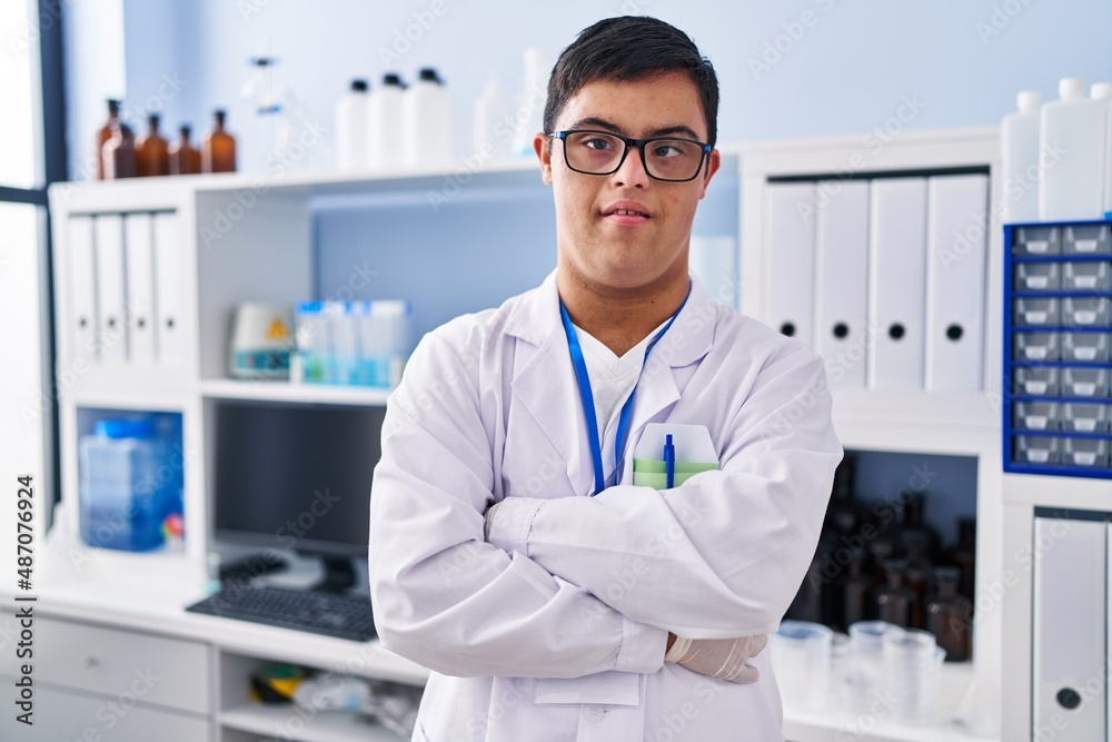Down syndrome man wearing scientist uniform standing with arms crossed gesture at laboratory Down syndrome man wearing scientist uniform standing with arms crossed gesture at laboratory
