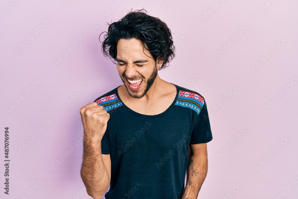 Handsome hispanic man wearing casual t shirt celebrating surprised and amazed for success with arms raised and eyes closed