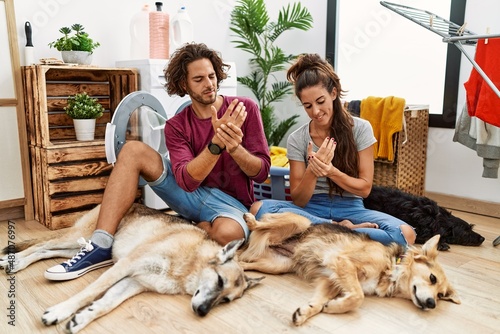 Photography Young hispanic couple doing laundry with dogs suffering pain on hands and finger