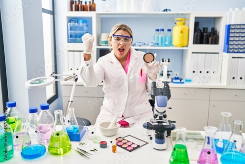 Young hispanic woman working at scientist laboratory doing make up annoyed and frustrated shouting with anger, yelling crazy with anger and hand raised