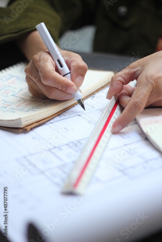 Hands of Asian female engineers are working on construction drawings on site.