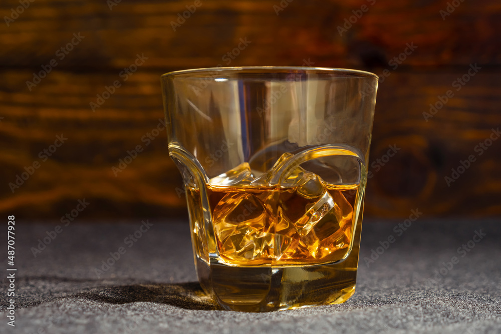 A glass of whiskey on ice against the dark boards. Close-up. A glass of whiskey on ice against the dark boards. Close-up.
