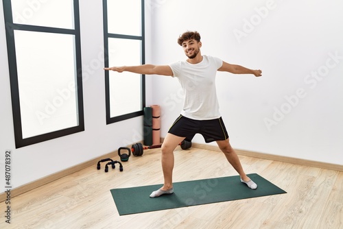 Young arab man smiling confident training yoga at sport center
